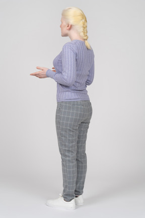 Three-quarter back view of a young blonde woman speaking