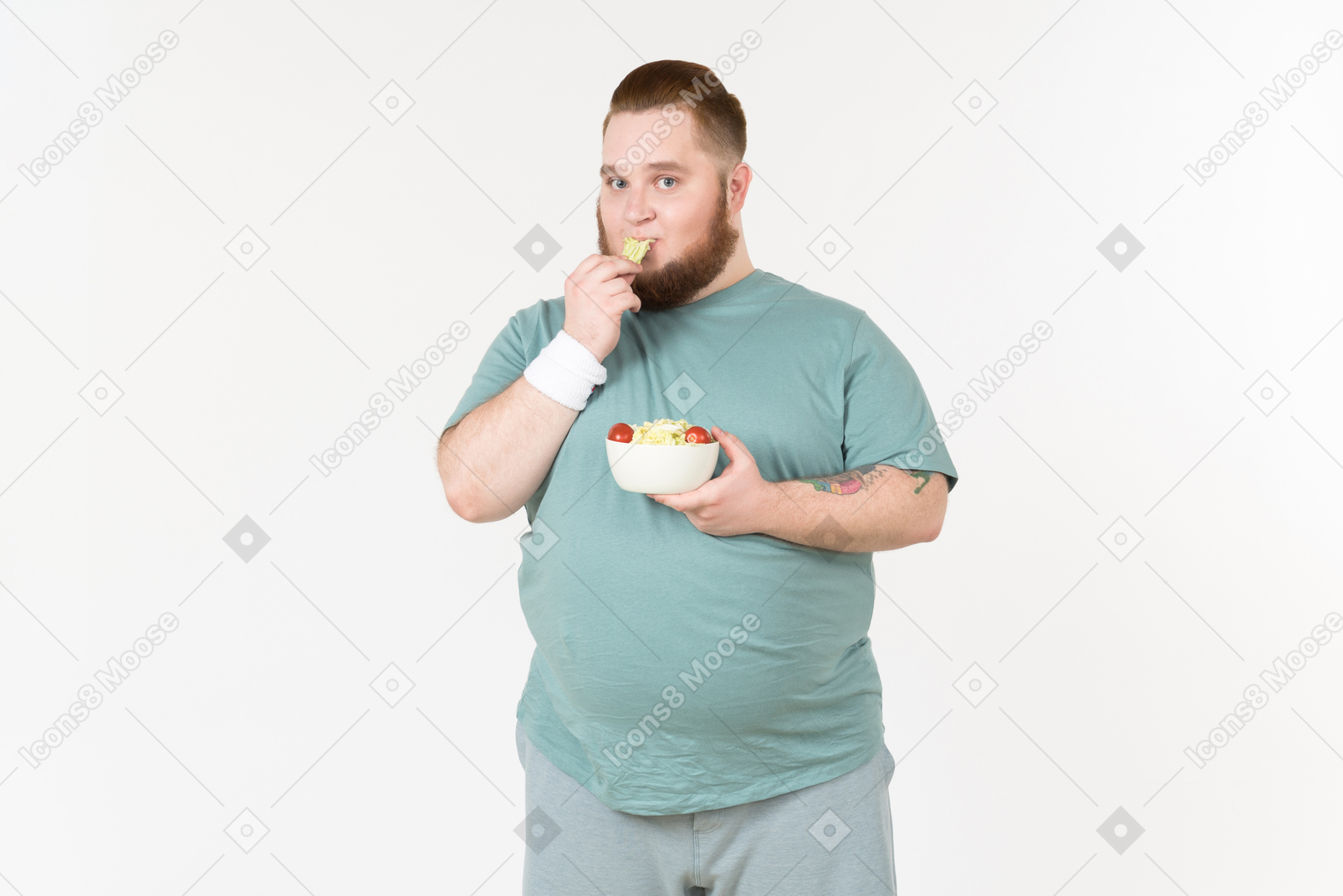 Ragazzo grande in abbigliamento sportivo raccogliendo foglie di insalata dal piatto