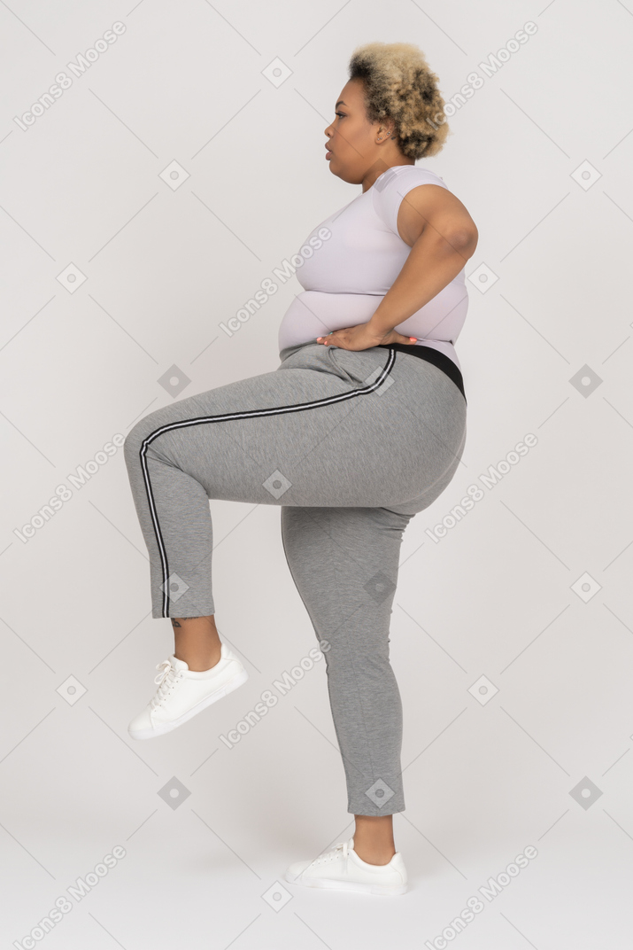 Plump woman balancing on one leg in profile