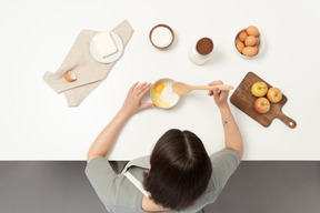 A female baker mixing eggs with flour