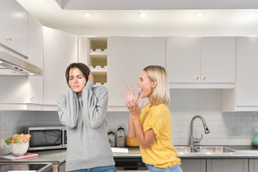 Young woman covering her ears from screaming woman