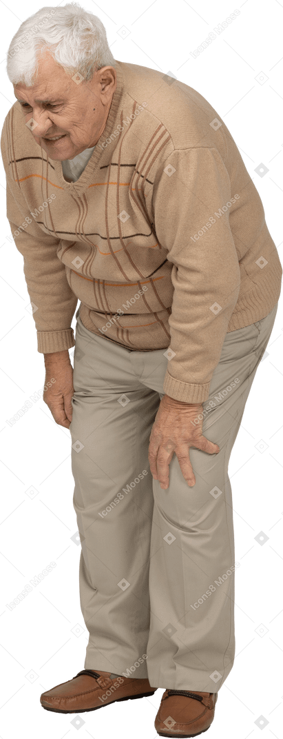 Vista frontal de um velho em roupas casuais, curvando-se e tocando seu joelho dolorido