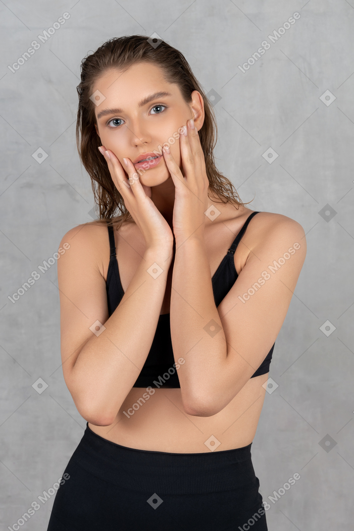 Mujer atractiva joven tocando sus mejillas