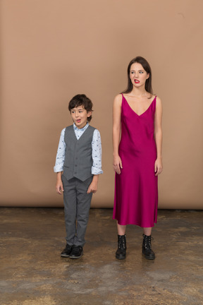 Front view of a grinning boy and woman in red dress