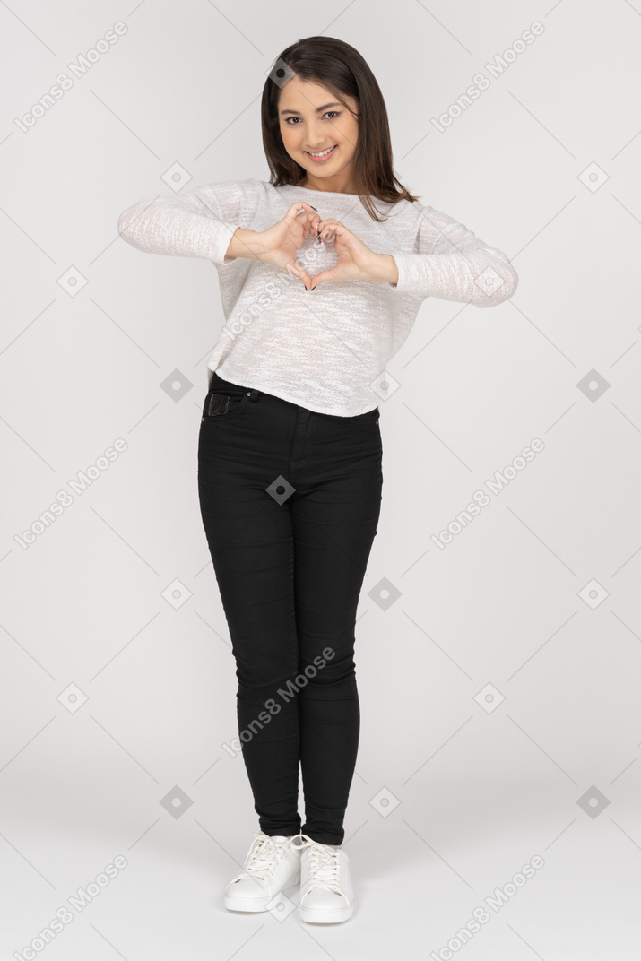 Front view of a young indian female in casual clothing showing heart gesture