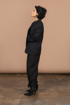 Vista lateral de uma mulher de negócios em um terno preto mostrando a língua
