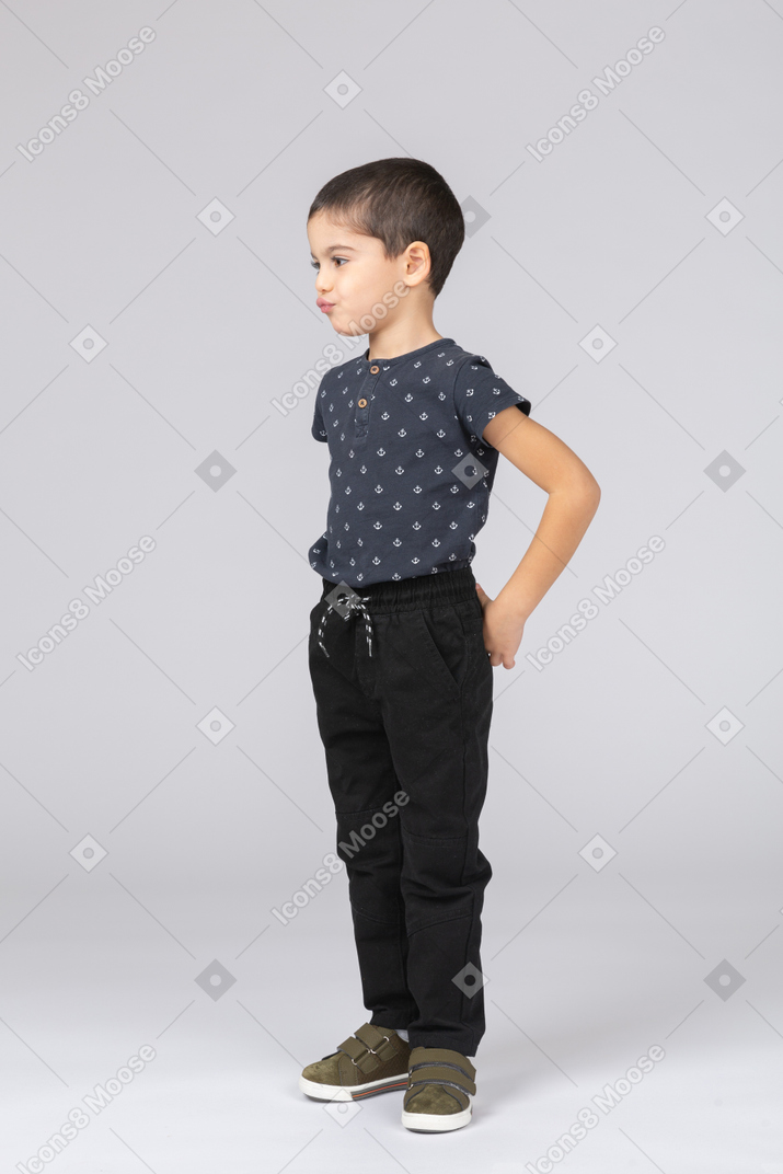 Vue latérale d'un garçon mignon dans des vêtements décontractés faisant des grimaces