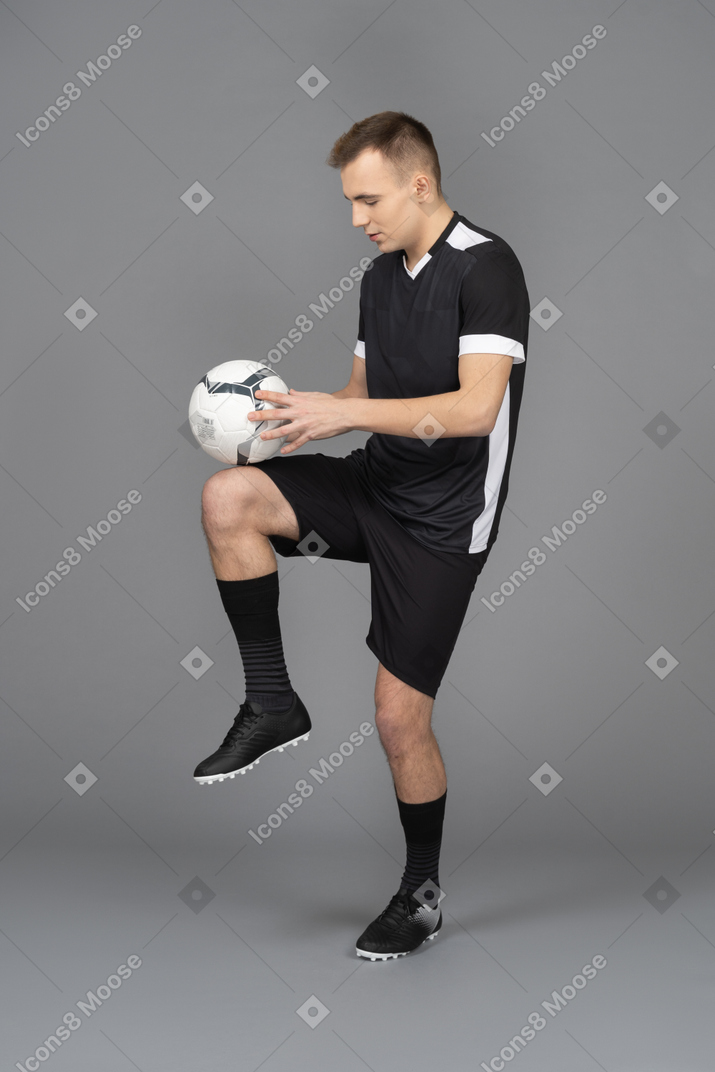 Vista laterale di un calciatore maschio calciare una palla