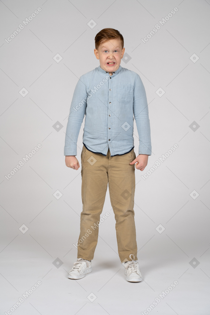 Vista frontal de um menino bravo com os punhos cerrados, olhando para a câmera