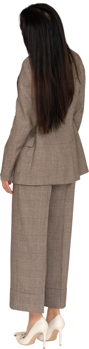 茶色のビジネススーツの傾いた頭の若い女性の4分の3の背面図