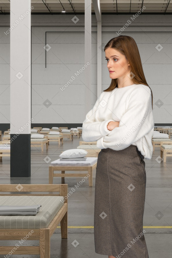 Woman with crossed arms standing in a room with beds