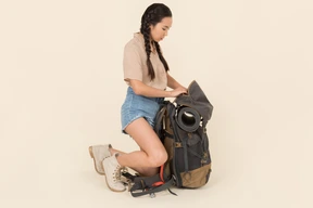 Joven viajero femenino asiático sentado cerca de la enorme mochila turística