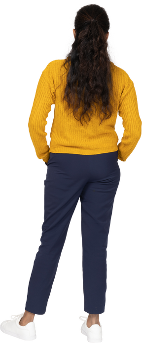 Back view of a girl in casual clothes posing with hands in pockets