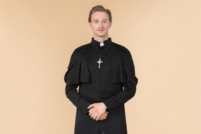 Catholic priest standing with his hands folded