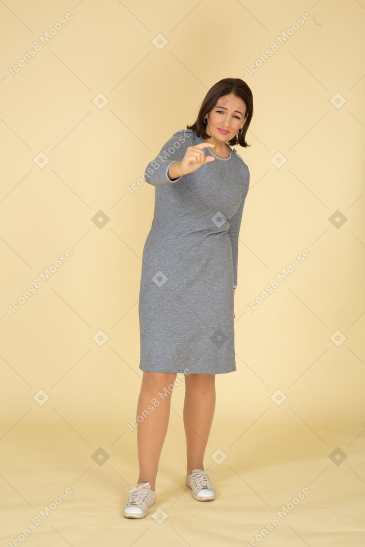 一个穿着灰色连衣裙的女人的前视图，显示出一个小尺寸的东西