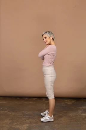 Side view of a happy woman in casual clothes posing with crossed arms