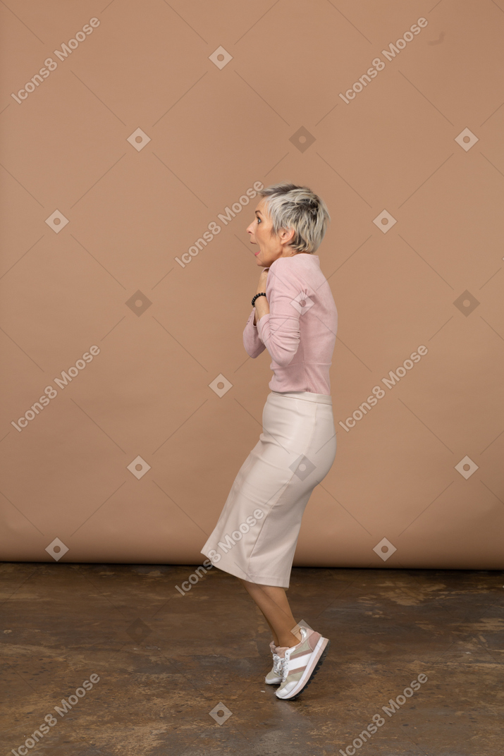 Vista laterale di una donna impressionata in abiti casual in piedi sulle dita dei piedi