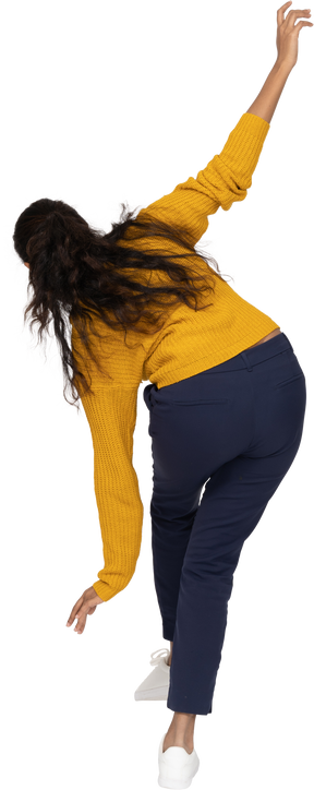 Vista posteriore di una ragazza in abiti casual in posa su una gamba con le braccia tese