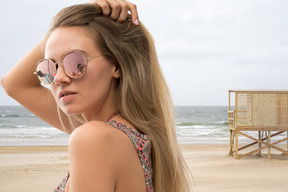 A woman with long hair and sunglasses on a beach