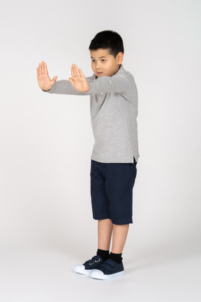 Vista frontal de um menino mostrando a placa de pare