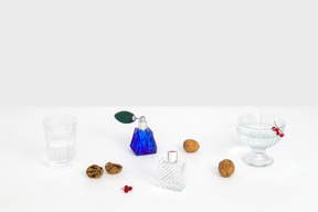 Retro perfume bottles, a dessert bowl, a glass of water and some walnuts