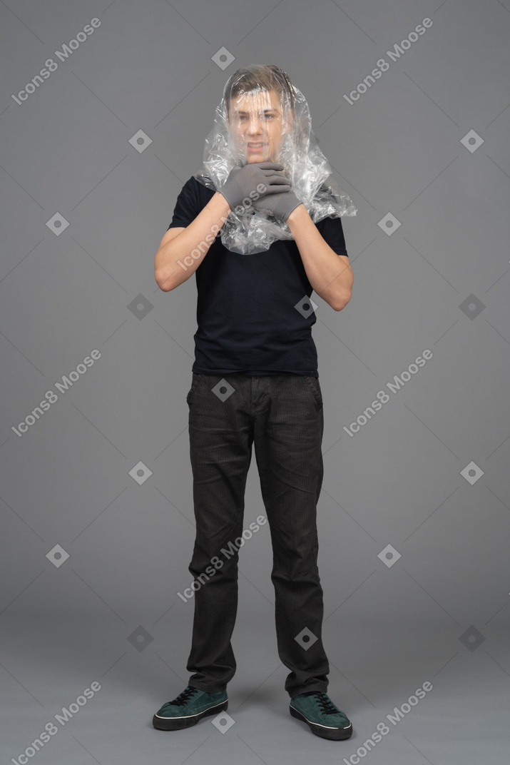 Male model on neutral background chokes himself with plastic wrap