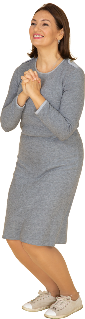 Vista frontal de uma mulher de vestido cinza fazendo um gesto de oração