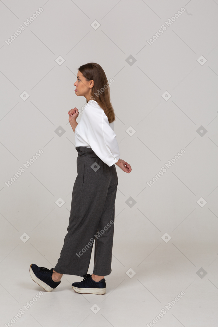 Side view of a confused young lady in office clothing raising hand