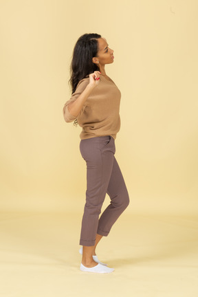 Side view of a sleepy dark-skinned young female stretching her back