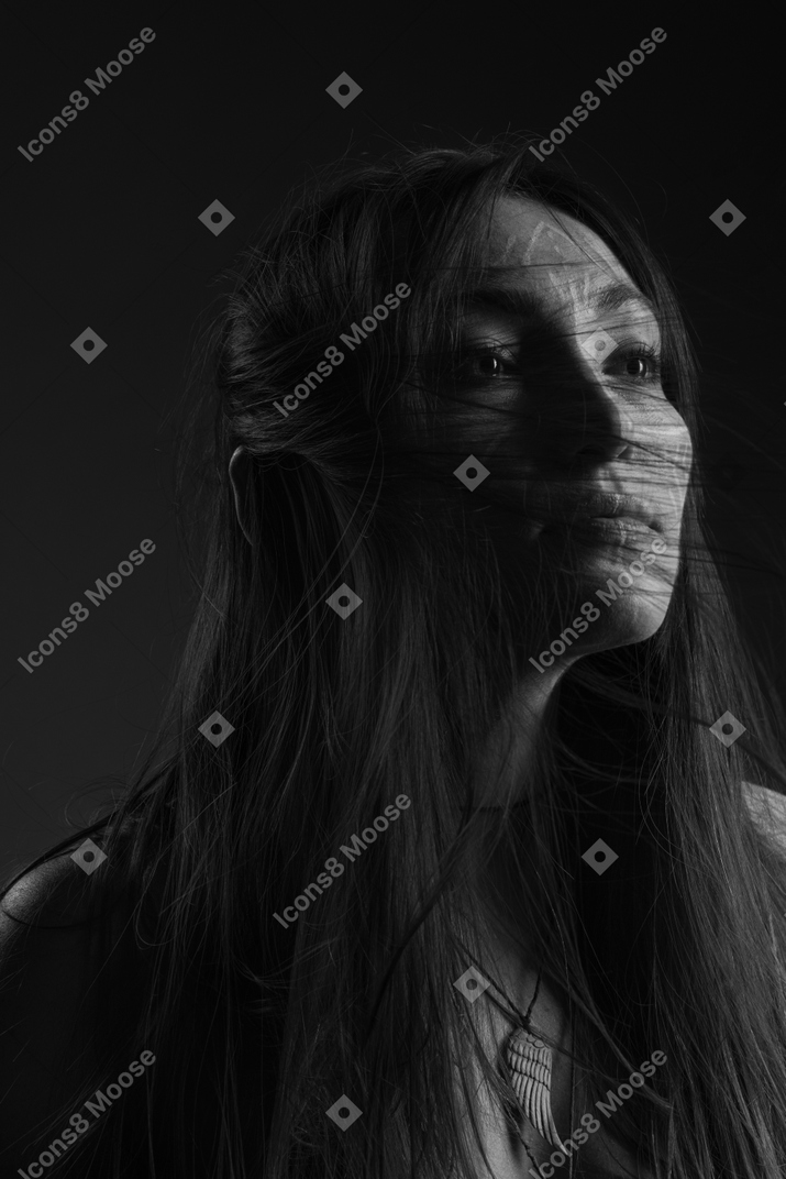 Noir three-quarter portrait of a young hopeful female with ethnic facial art and messy hair