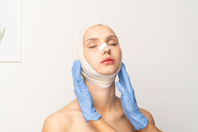 Young woman with bandaged head and hands on her face