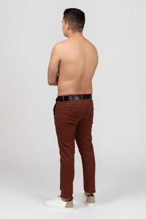 Three-quarter back view of a shirtless latino man with folded hands