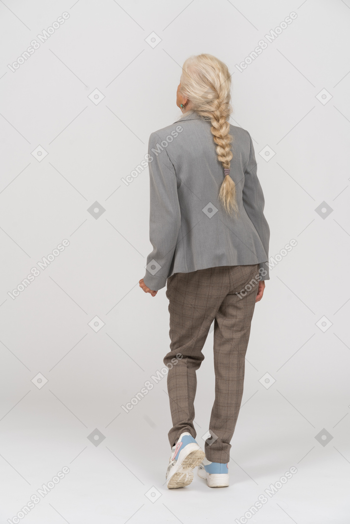 Vista posteriore di una vecchia signora in abito posa su una gamba sola