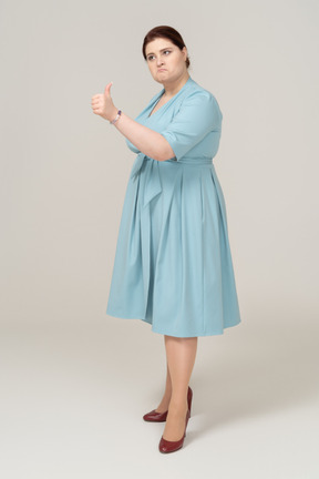 Vista laterale di una donna in abito blu che mostra il pollice in su