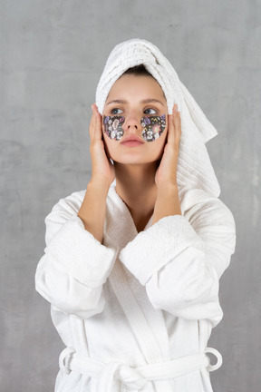 Woman in bathrobe holding her face