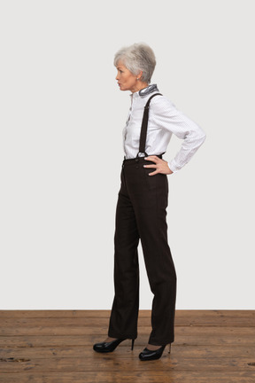 腰に手を置くオフィス服の不機嫌な老婦人の側面図