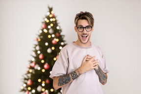 Chico joven inconformista cerca de un árbol de navidad