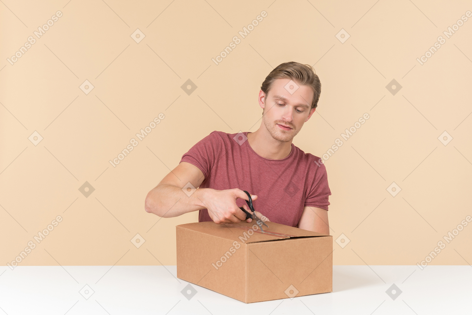 Young guy opening a parcel with scissors