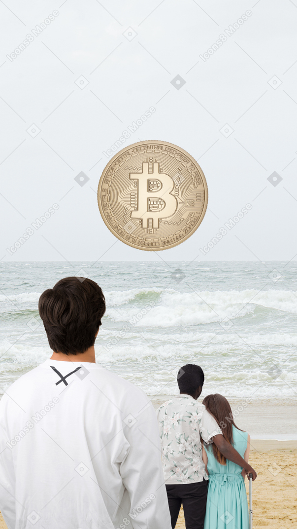 A man and woman standing on a beach with a bitcoin in the air