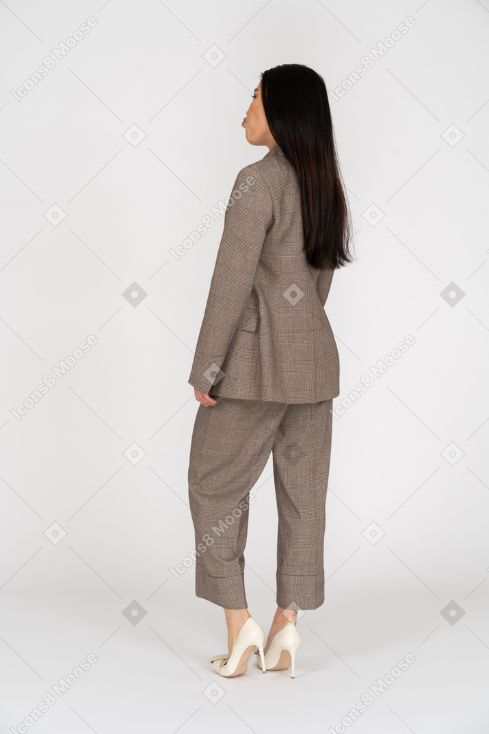 Three-quarter back view of a pouting young lady in brown business suit. while raising head