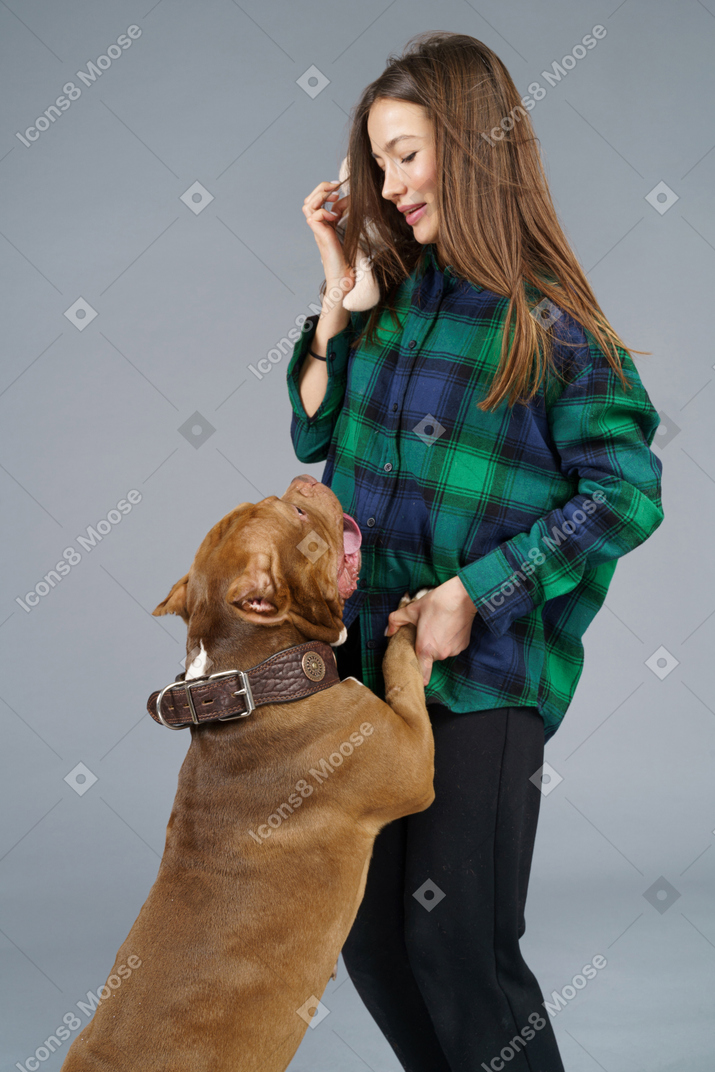 Close-up of a brown bulldog playing with surprised female master looking at her pet