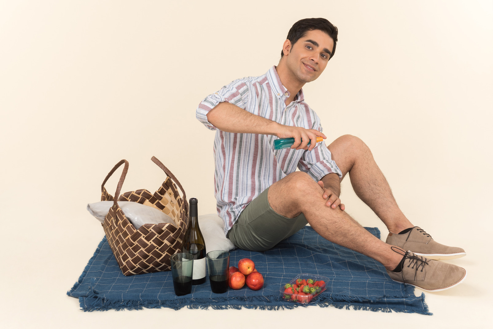 Young caucasian man sitting on blanket andspraying a spray on his leg