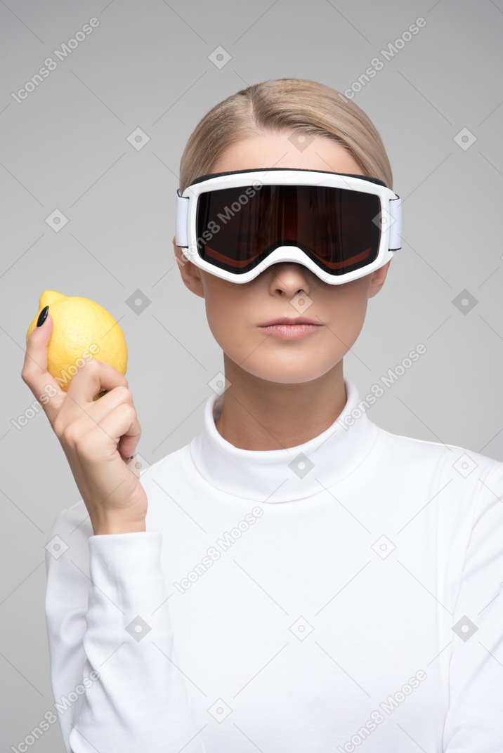 Joven rubia con gafas de esquí sosteniendo limón