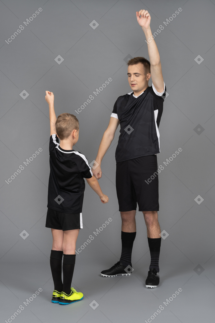 Молодой человек тренирует маленького мальчика в полный рост, делая разминку