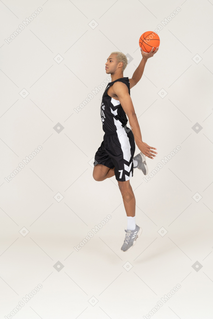 Side view of a young male basketball player scoring a point