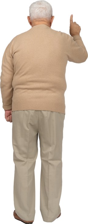 Vista posteriore di un uomo anziano in abiti casual che punta verso l'alto con il dito