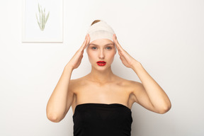 Mujer joven con la cabeza vendada tocando las sienes