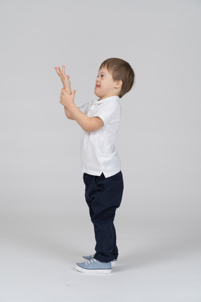 Vista lateral del niño feliz levantando la mano