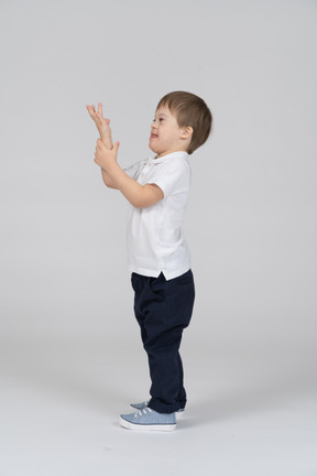 Side view of happy boy raising his hand