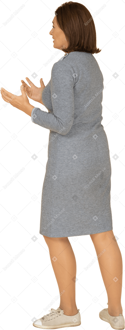 Vista lateral de uma mulher triste em um vestido cinza gesticulando
